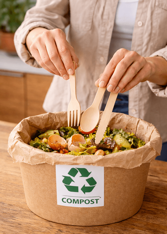 Couverts en bois jetés dans un bac de compost après utilisation en restauration