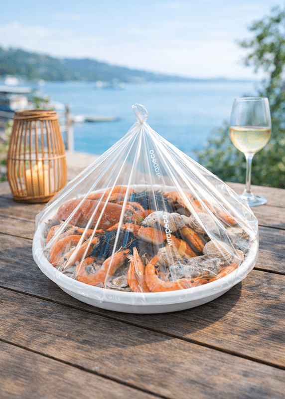Plateau de fruits de mer emballé avec une housse Wrapeco sur table en bois en extérieur